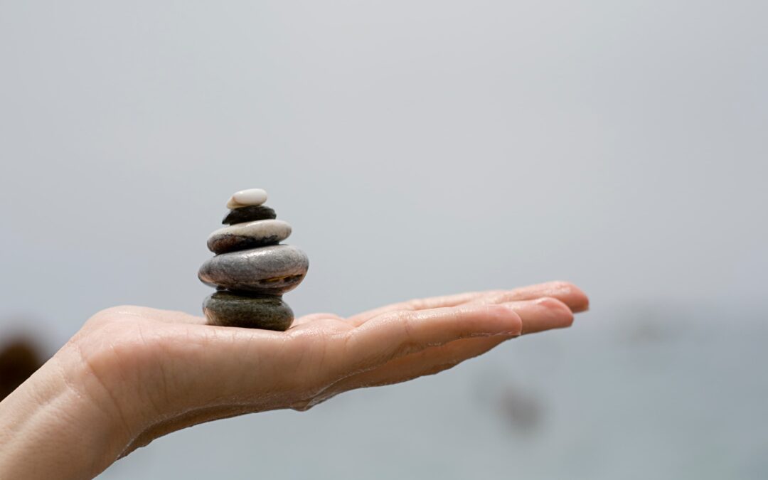 hand holding pile stones symbolising balance and wellness